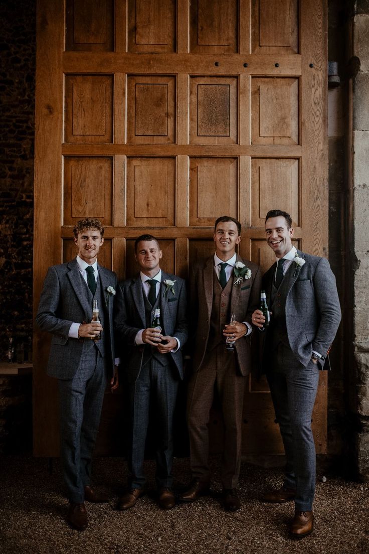 three men in suits standing next to each other near a wooden paneled wall and door