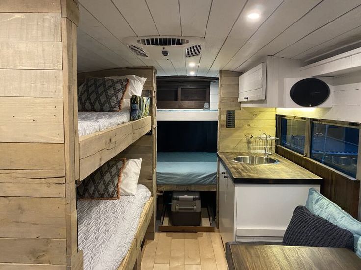 the interior of a small rv with bunk beds and couches in it, next to a kitchen