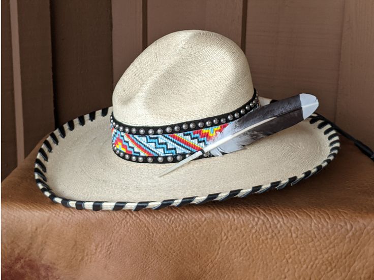 I fashioned this hat after being inspired by the intricate Native American Indian headdresses. This is a palm leaf Gus hat body . It has a 4" brim and a 5 1/4" crown. It is hand laced in black leather lace. The hatband has a base of black suede that is then decorated with two rows of nailspots and finished with this incredibly colorful beaded hatband. Black tassels for that extra accent. And check out the Harris Hawk feather which is actually a turkey feather that has been trimmed and hand paint Artisan Toquilla Straw Hat For Rodeo, Natural Toquilla Straw Hat With High Crown, Artisan Fitted Hat For The Beach, Handmade Straw Hat For Kentucky Derby And Rodeo, Handmade Straw Hat For Rodeo And Kentucky Derby, Artisan Straw Hat With Curved Brim For Country Events, Traditional Fitted Wide Brim Hat, Traditional Wide Brim Fitted Hat, Traditional Straw Hat For Summer Rodeo