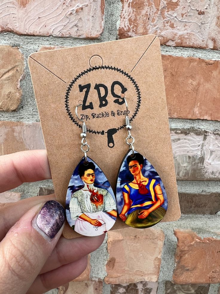 a pair of earrings with the image of two women on them