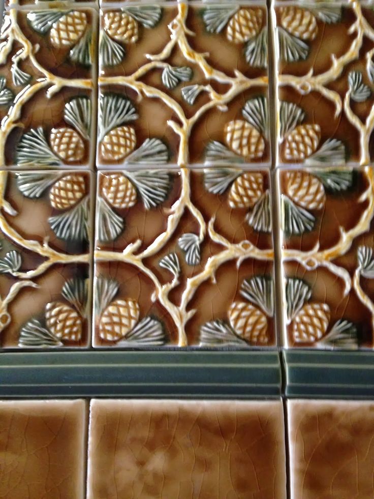 decorative tile with pineapples and leaves on the bottom, brown tiles in the background