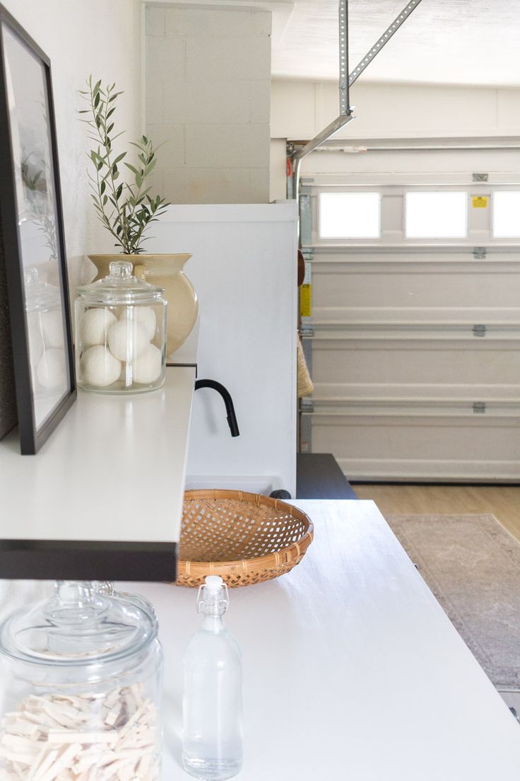 a white table topped with bottles and vases next to a shelf filled with candles