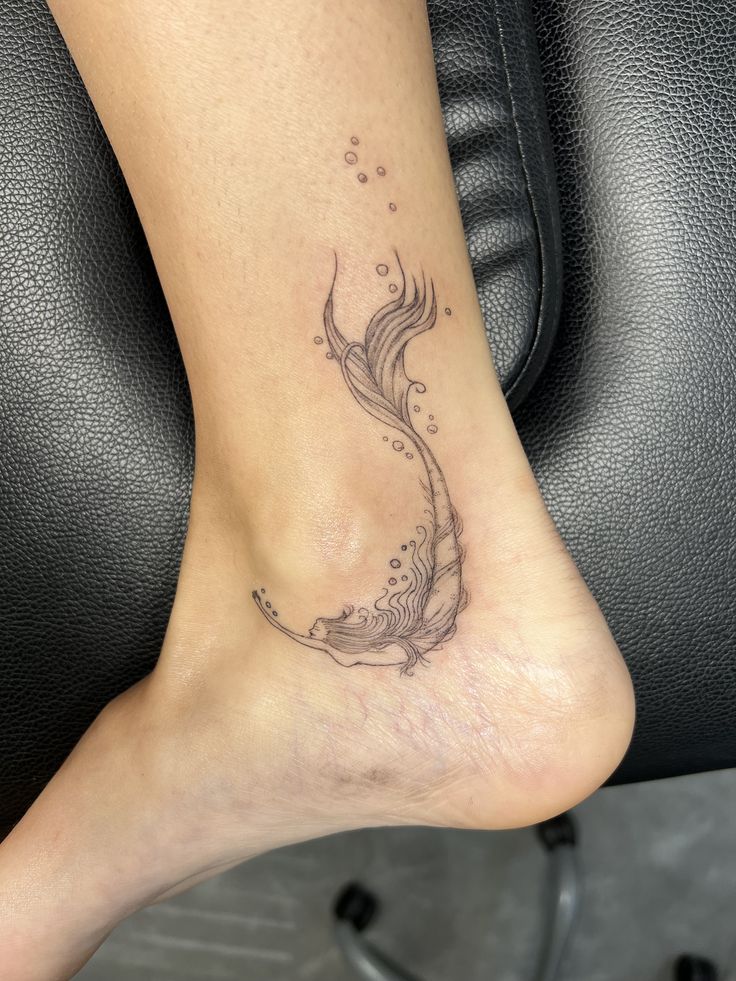 a woman's foot with a fish tattoo on the side of her leg,