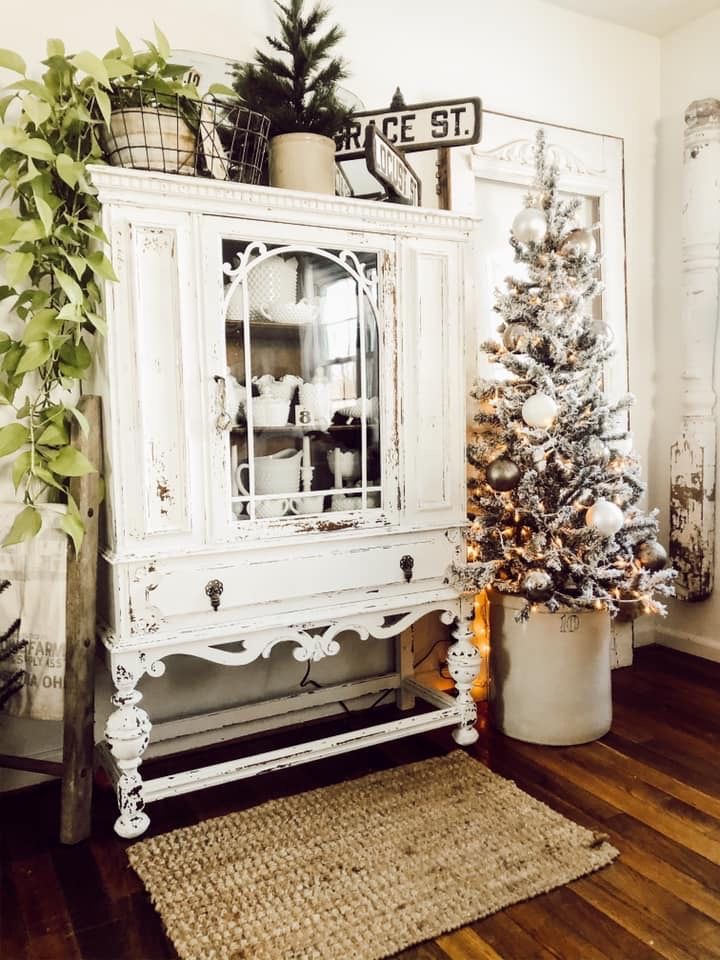 a white china cabinet sitting next to a christmas tree