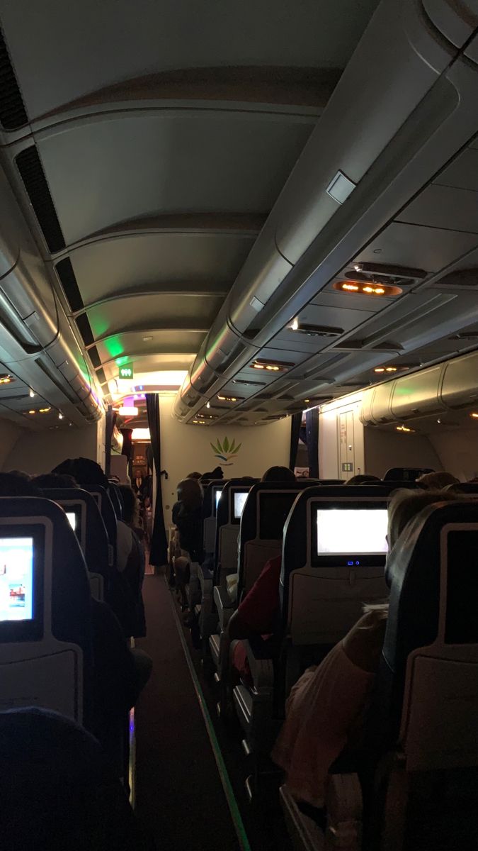 the inside of an airplane with people sitting in seats and watching televisions on their screens