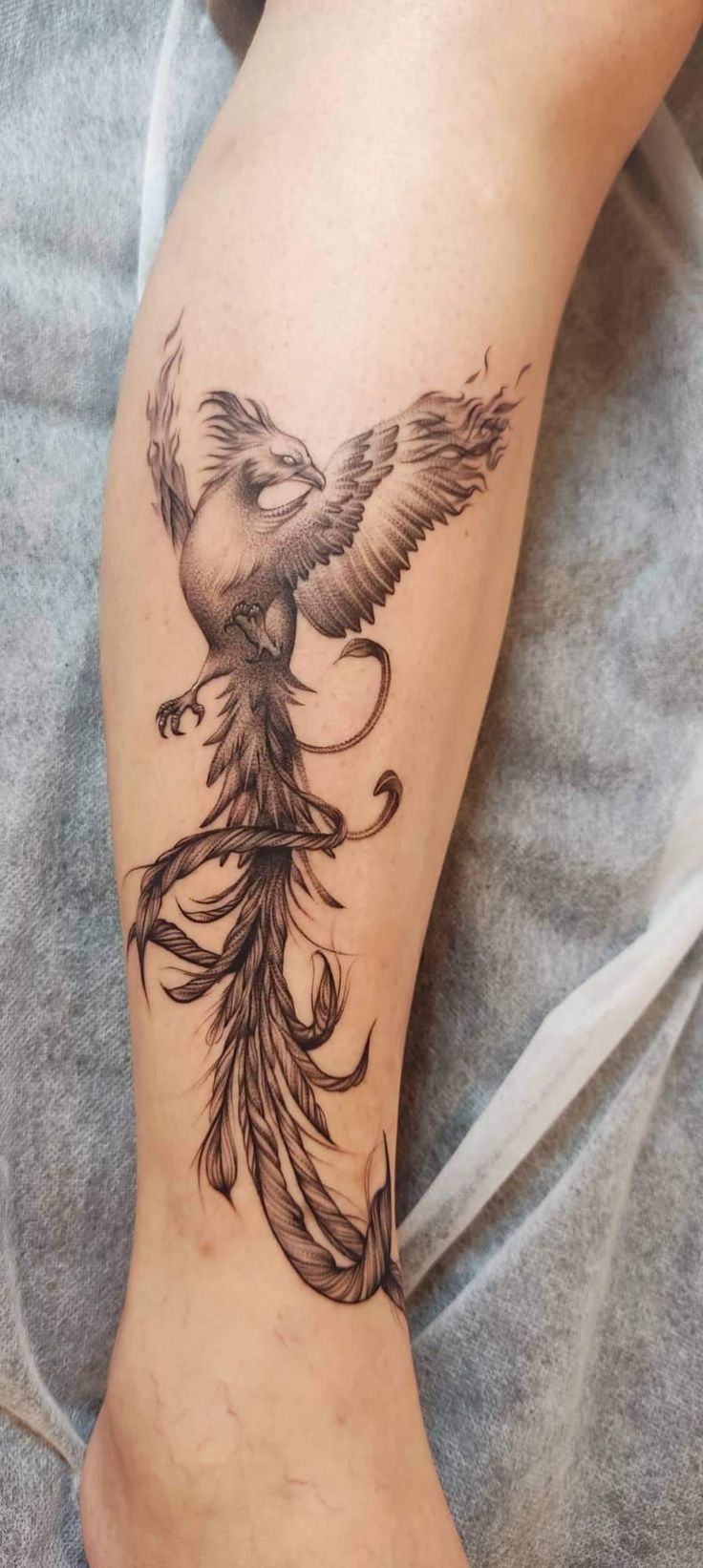 a tattoo on the leg of a woman with a bird flying above her head and an arrow