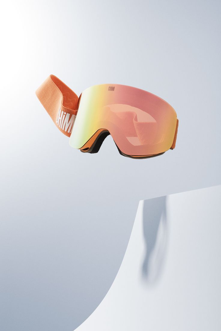 an orange pair of ski goggles flying through the air over a snow covered slope