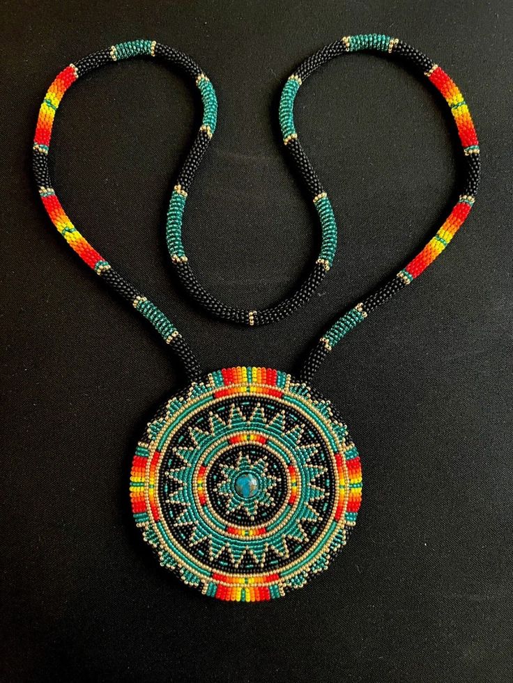 a necklace made with beads and beading on a black surface, including a circular pendant