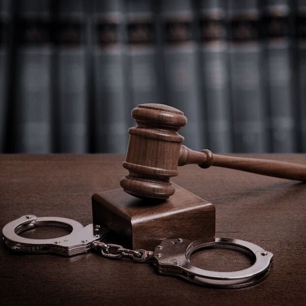 a wooden judge's gaven sitting on top of a table next to handcuffs