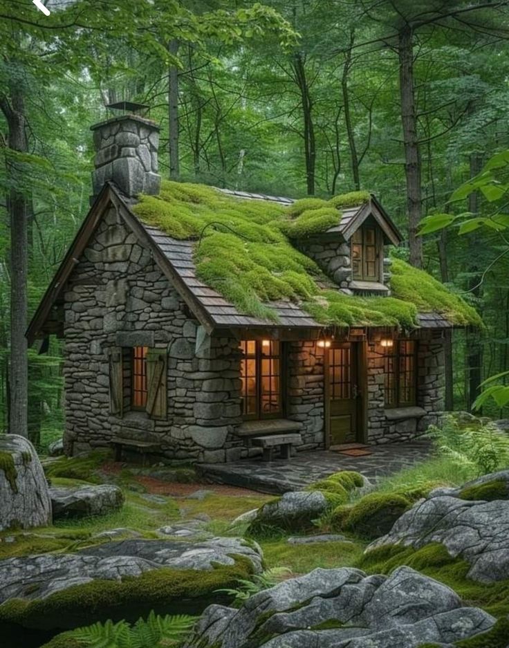 a small stone cabin with moss growing on the roof and windows is surrounded by rocks and trees