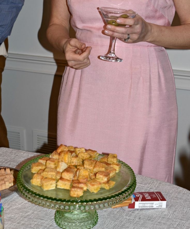 a woman in a pink dress is holding a wine glass and looking at some food