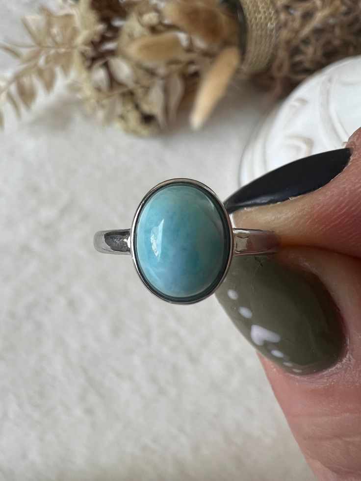 The Larimar ring in stainless steel, adjustable in size, is a piece of jewelry that carries the beauty of the Caribbean Sea. The ring's adjustable size allows it to be customized to fit different finger sizes, providing a comfortable and flexible wearing experience. The soft color of the Larimar is reminiscent of clear oceans and brings a calming and refreshing energy. Larimar is often associated with peace, calm and relaxation. Wearing this ring could therefore not only be fashionable but also serve as a symbol of serenity and inner balance. This Larimar ring, which is also size-adjustable, is not only a stylish accessory, but also an expression of natural beauty and relaxed elegance. Nickel-free Stainless Steel Round Rings, Adjustable Nickel-free Stainless Steel Rings, Adjustable Stainless Steel Nickel-free Rings, Adjustable Larimar Jewelry For Anniversary, Stainless Steel Oval Rings For Gifts, Hypoallergenic Stainless Steel Rings, Adjustable Oval Turquoise Promise Ring, Nickel Free Stainless Steel Rings For Gifts, Nickel-free Stainless Steel Rings As Gift