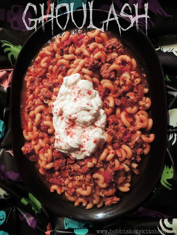 a bowl filled with pasta and sauce on top of a black plate next to halloween decorations