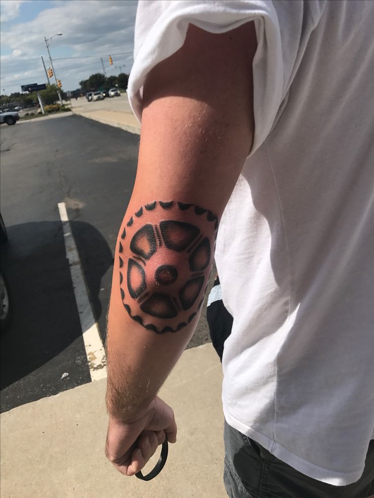 a man with a tattoo on his arm holding onto a bike tire in the parking lot