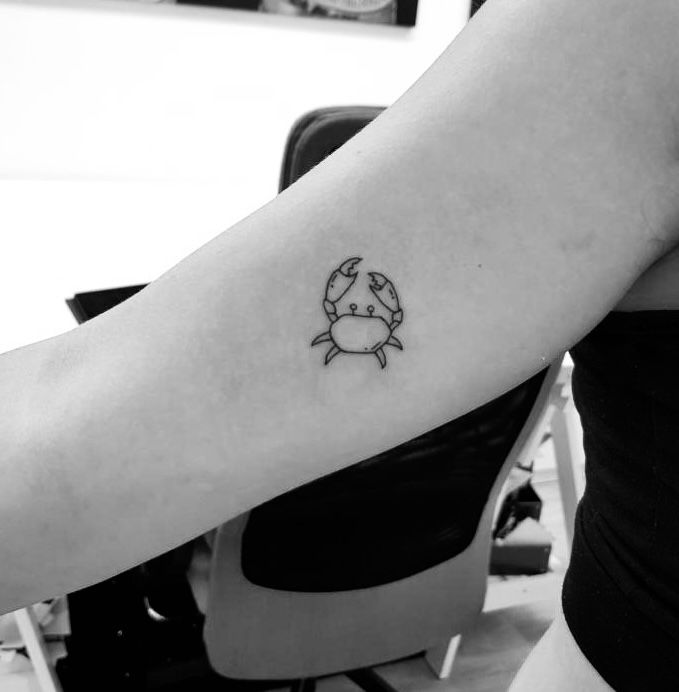 a woman's arm with a small crab tattoo on the left side of her arm