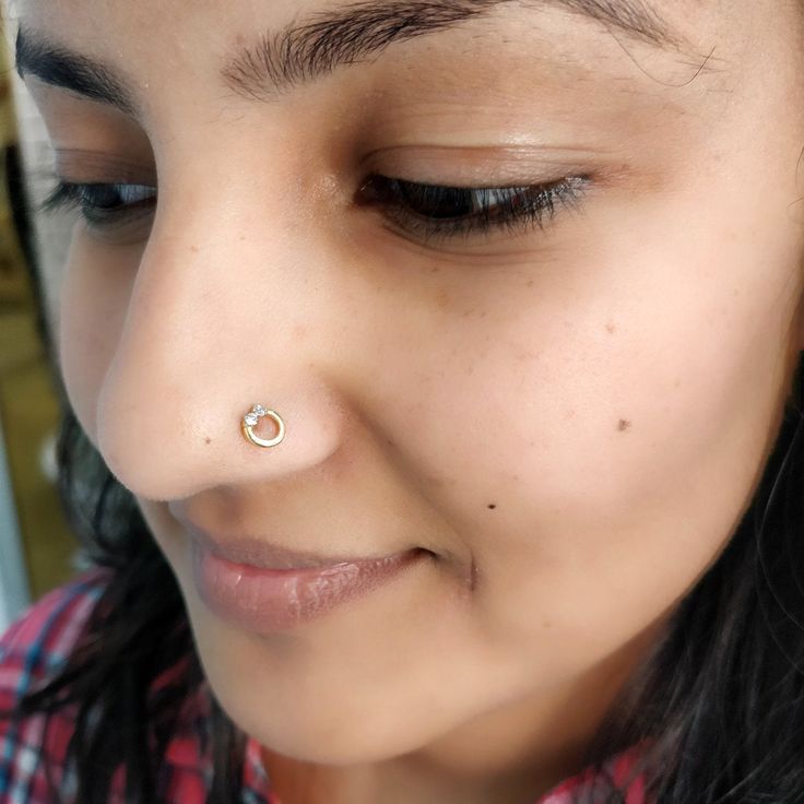 a close up of a person wearing a nose ring with a piercing on her nose