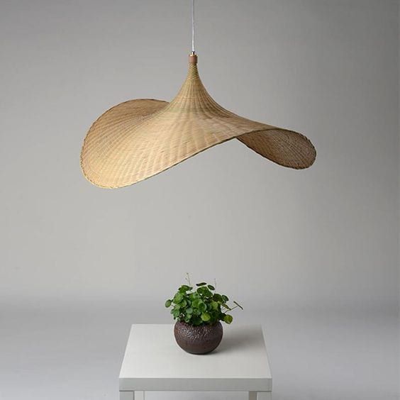 a potted plant sitting on top of a white table next to a hanging lamp