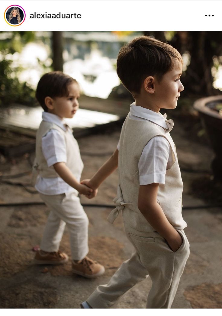 two young boys are holding hands and walking