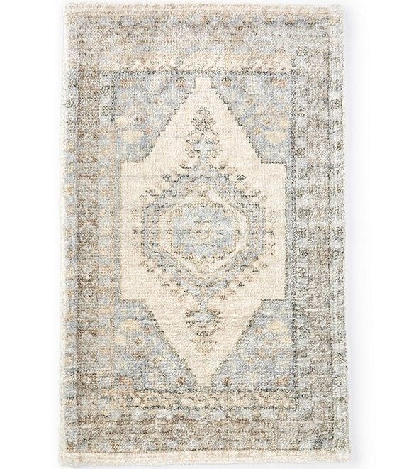 a rug with an ornate design on the front and back side, in grey tones