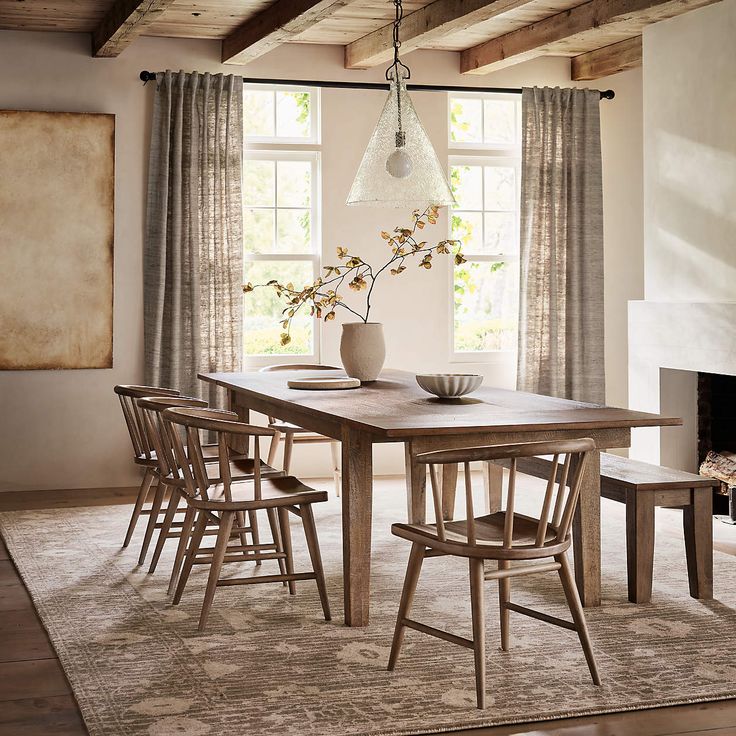 a dining room table with six chairs and a vase on top of it in front of a fireplace