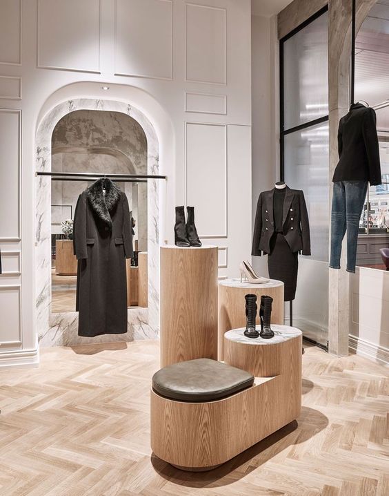 a store display with mannequins, jackets and shoes on wooden benches in front of windows