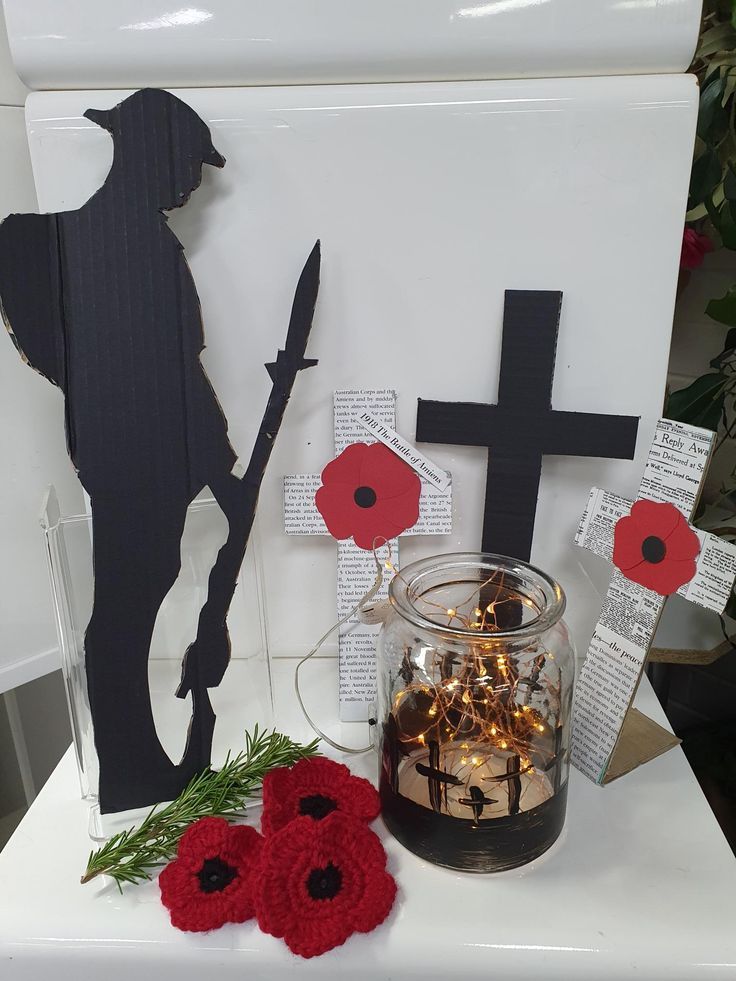 a table topped with a vase filled with red flowers and two crocheted crosses