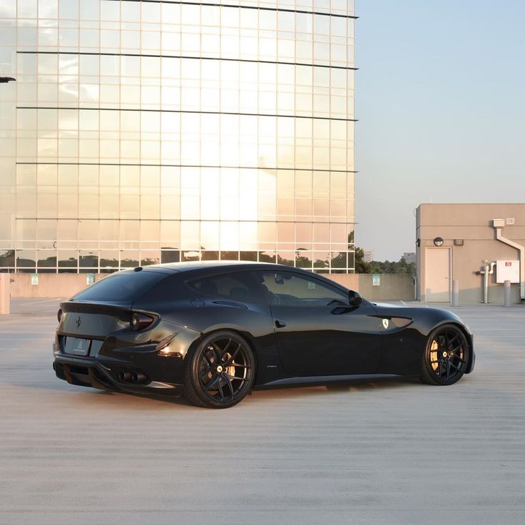 a black sports car parked in front of a tall building