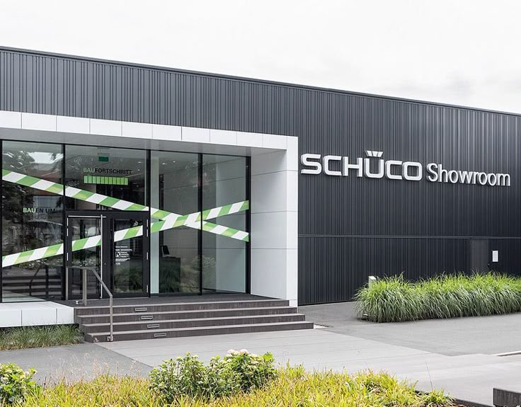 a black and white building with stairs leading up to it's entry door that says schuco showroom