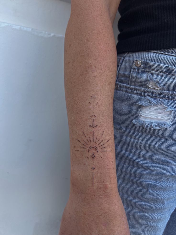 a woman's arm with a tattoo on it that has an arrow and sun