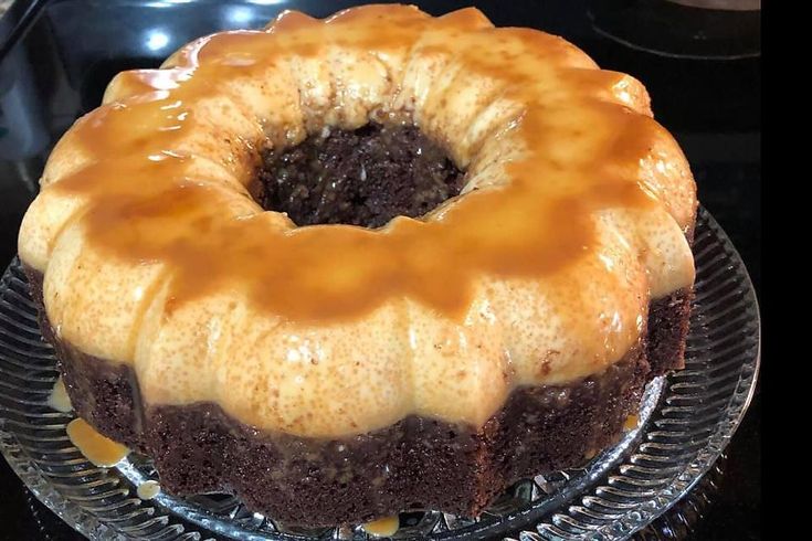 a chocolate bundt cake with caramel glaze on top sitting on a glass plate