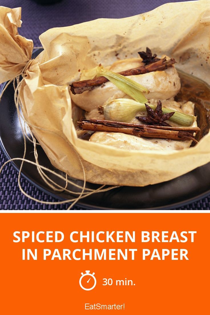 there is a paper bag filled with chicken breast in parchment paper on top of a black plate