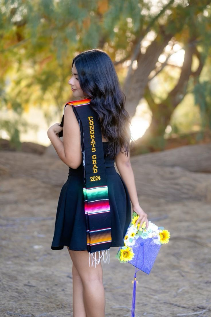 a woman in a black dress holding a bouquet of flowers and a blue ribbon around her neck