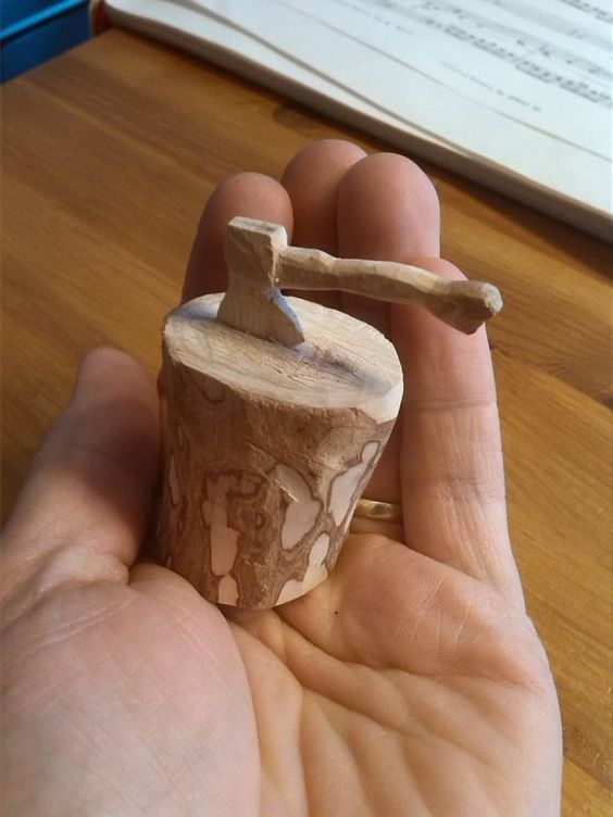 a person holding a small piece of wood in their hand with an hammer stuck into it