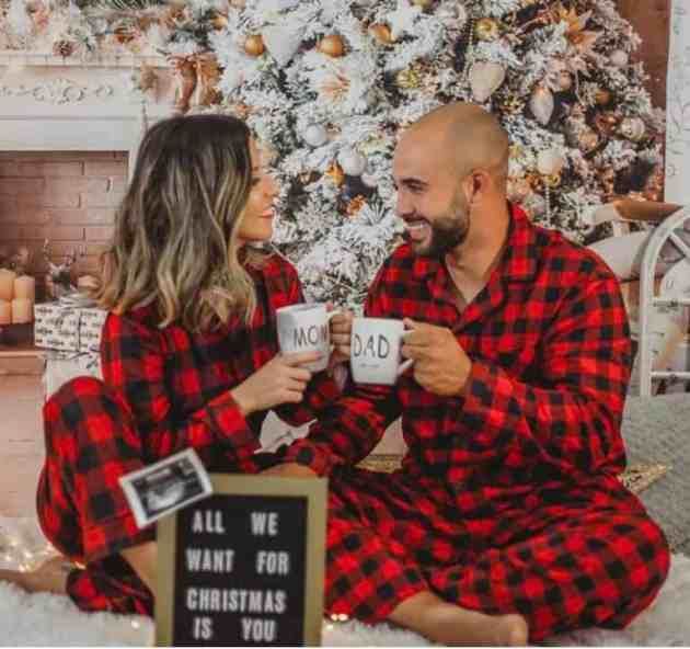 a man and woman sitting in front of a christmas tree holding mugs with the words, all we want for christmas is you