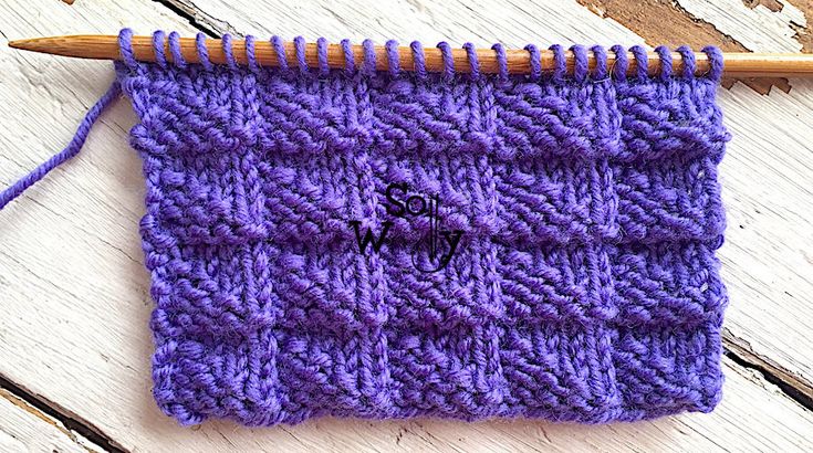 a purple knitted object with a wooden knitting needle