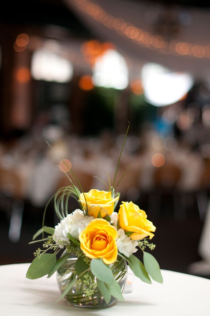 a vase filled with yellow and white flowers on top of a table in a room