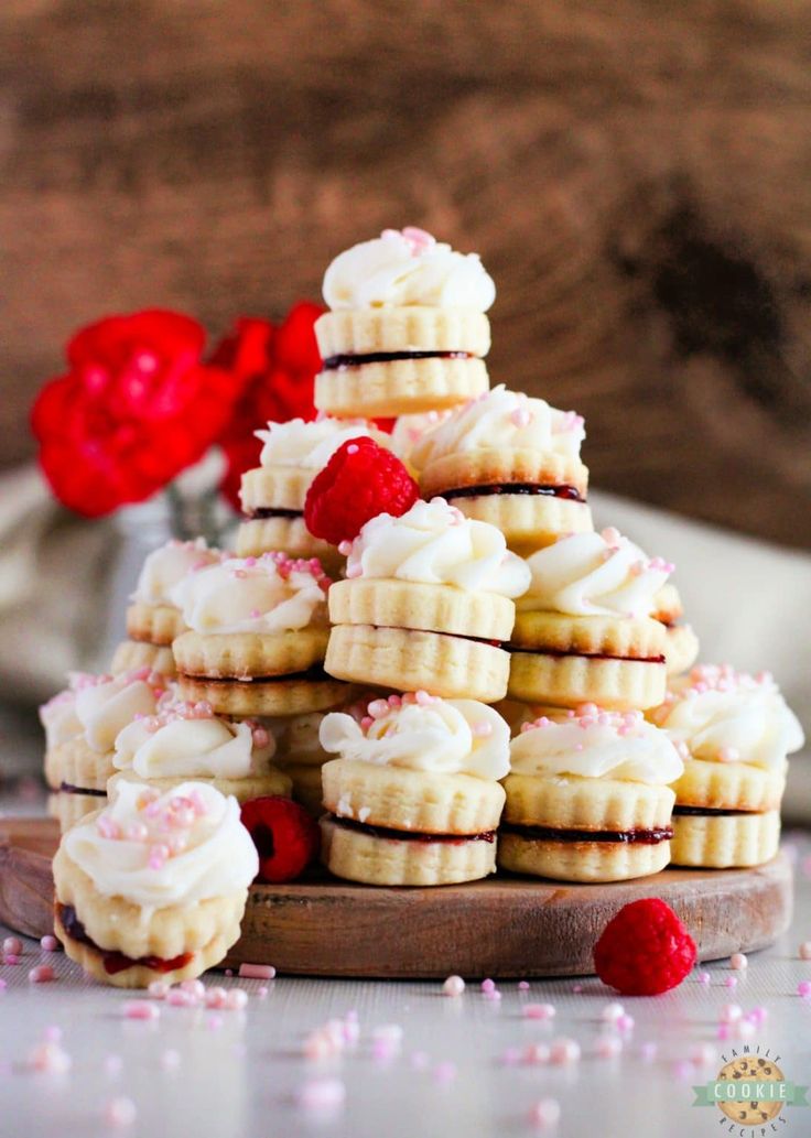 a stack of cookies with white frosting and raspberries