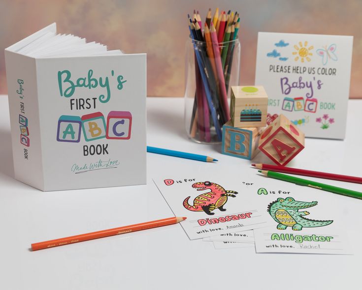 the baby's first abc book is next to colored pencils and crayons