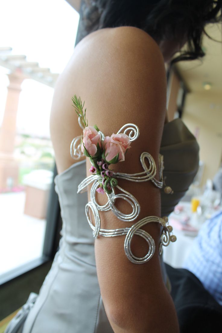 a woman in a gray dress with flowers on her arm and bracelets around her waist