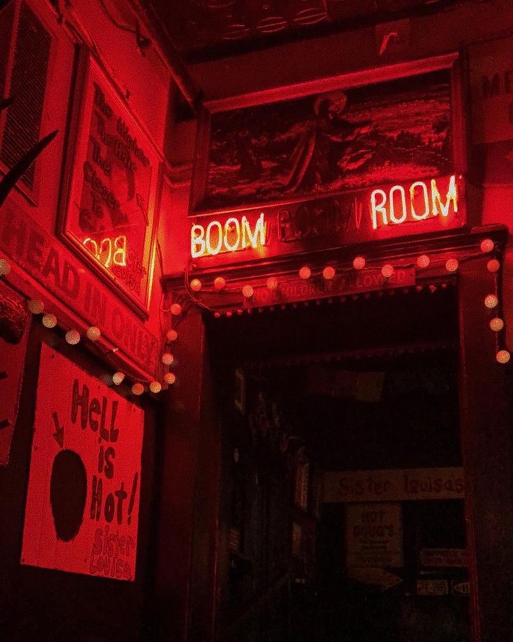 red neon signs are lit up above the doorway to a room that has been decorated with posters and lights