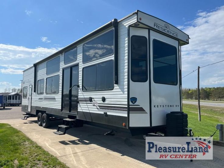 a white trailer parked on the side of a road next to a sign that says pleasure land rv center