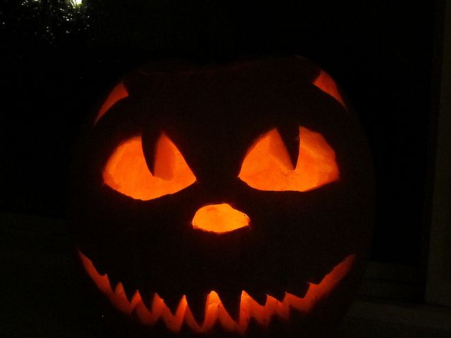 a carved pumpkin with glowing eyes in the dark