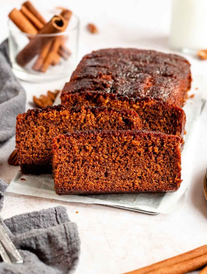 sliced loaf of chocolate pumpkin bread on a plate with cinnamon sticks and glass of milk