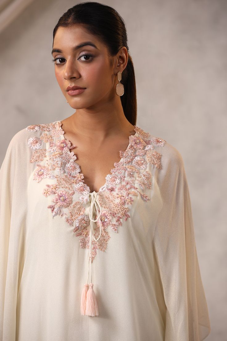 Off white kaftan crafted in georgette with floral sequin and bead embroidered neckline and a front tie-up detail. Comes with an inner. Components: 2 Pattern: Embroidered Type Of Work: Resham, Bead, Sequin Neckline: V Neck Sleeve Type: Asymmetric Fabric: Georgette Color: Off White Other Details:  Attached lining Kaftan length: 58 inches Model Height: 5ft 6inches, wearing size M Occasion: Mehendi and Haldi - Aza Fashions Kaftan Pattern, Kaftan Women, White Kaftan, Kaftan For Women, Embroidered Kaftan, Beaded Neckline, Embroidered Neckline, Indian Designer, Indian Designer Wear