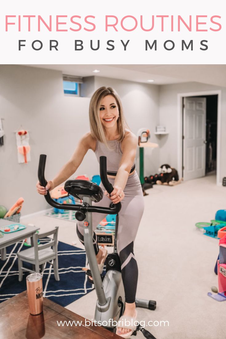 a woman riding an exercise bike in her home gym with text overlay that reads, fitness routine for busy moms