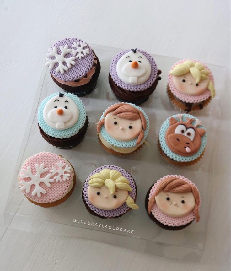 cupcakes decorated with frosting and icing are arranged on a clear tray