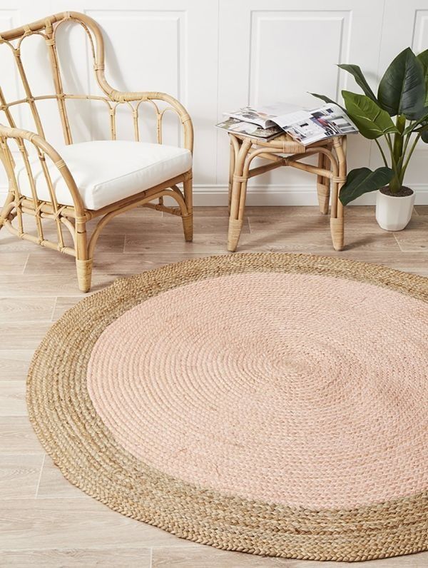 a large round rug in the middle of a room with chairs and a potted plant