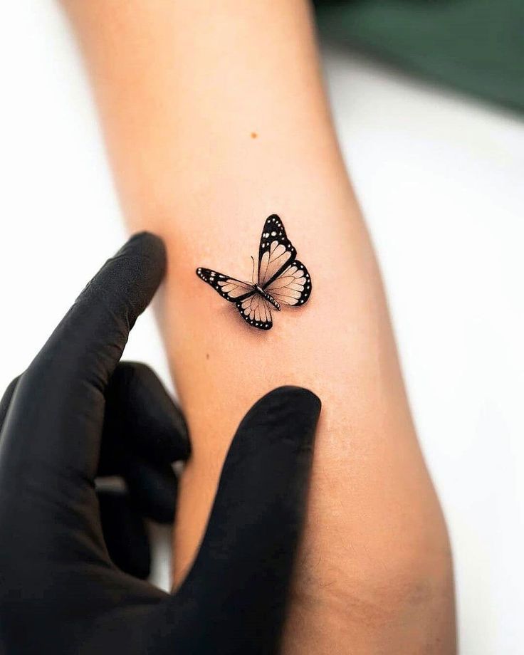 a woman's arm with a small butterfly tattoo on the left side of her arm