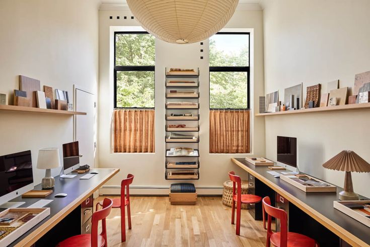 an office with desks, chairs and bookshelves in front of a window