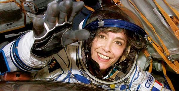 a woman in an astronaut's spacesuit is making the peace sign with her hand